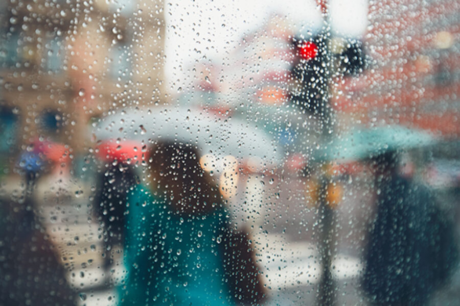 Gloomy day in the city. People in heavy rain. Selective focus on the raindrops. Prague, Czech Republic.