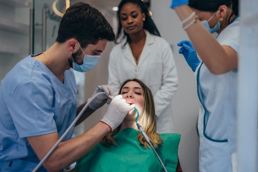 Portrait of Caucasian beautiful woman patient smiling and receiving treatment from professional dentist doctor for an oral care check up about cavities and gum disease in a dental clinic.